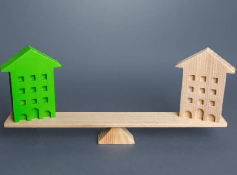 two houses sitting on a see-saw as a visual representaion of balancing a target property against its comparable market sale within an analysis.